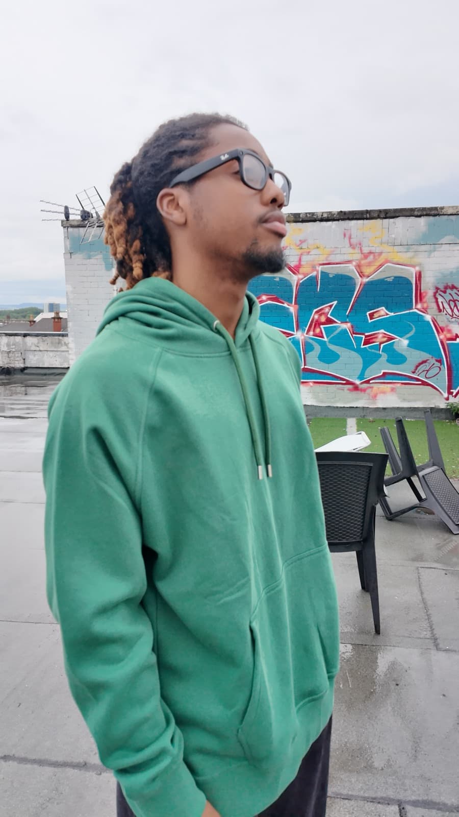 Model in a green hoodie in front of a graffiti wall