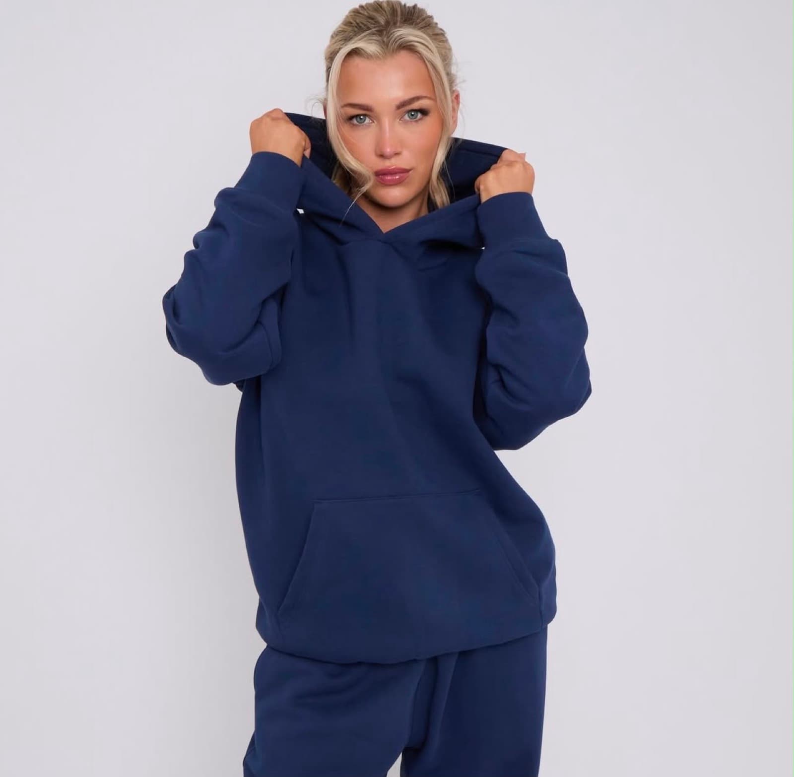 Model in a navy oversized hoodie with the hood up