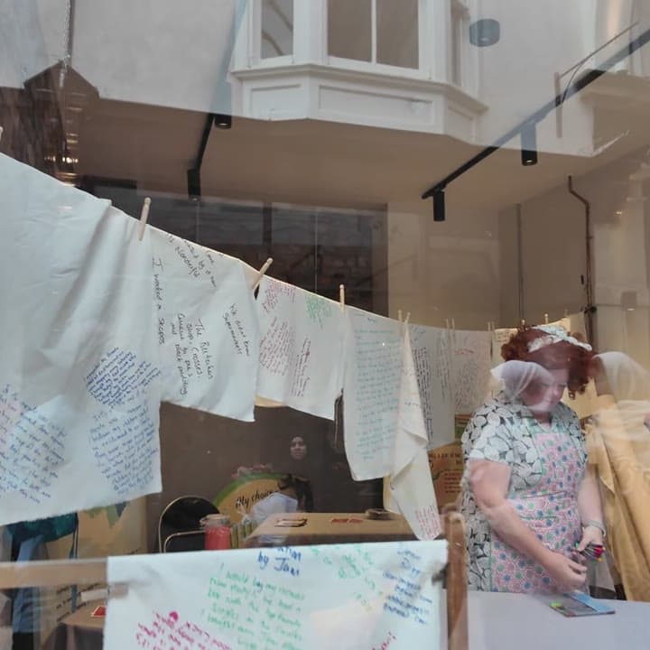 Cloth and hand-written textiles strung on a line in a shop window