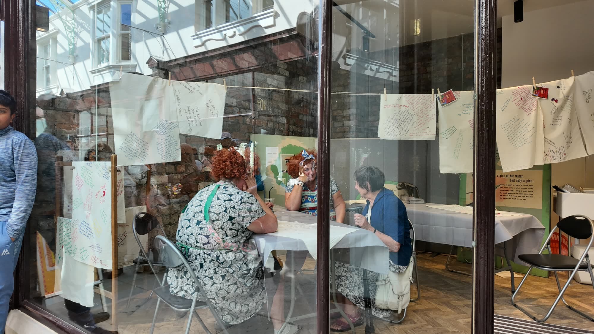 Makers working at tables seen through the arcade shop glass